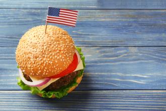 Top view of burger with American flag toothpick on blue wooden table