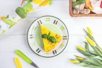 Homemade quiche and tulips on white wooden background