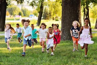 A group of children running in the park on a sunny day 