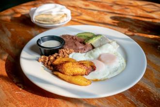 A Latin American breakfast of eggs, plantains, refried beans, cheese, avocado, and tortillas.