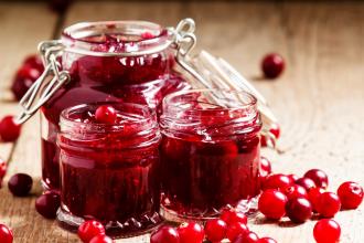 cranberry jam in glass jars and fresh cranberry on a wooden table